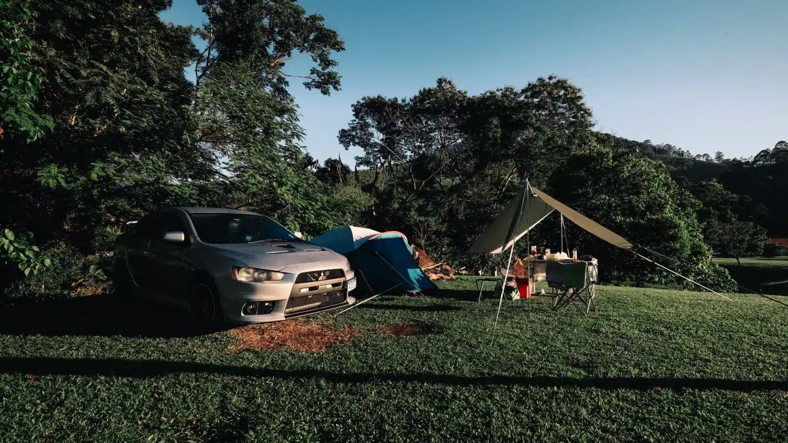 Aire de camping-car gratuite en bord de lac, avec un véhicule aménagé stationné sous les arbres