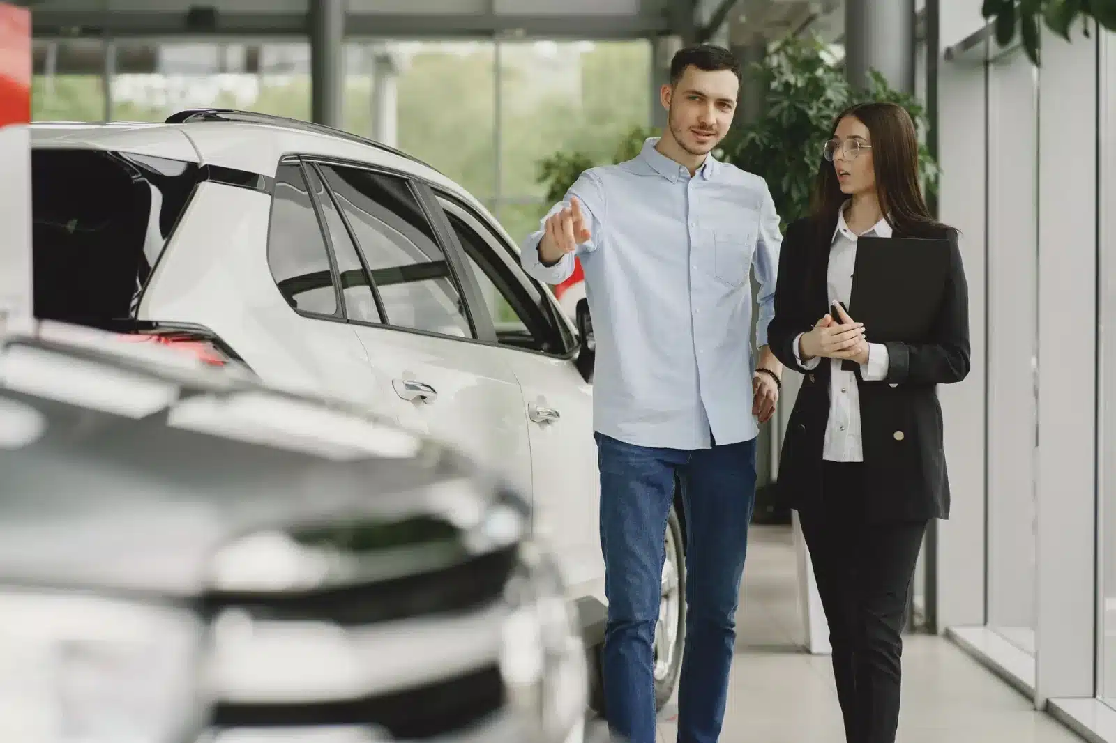 Couple discutant avec un conseiller en concession pour l'achat d'une voiture électrique avec bonus écologique