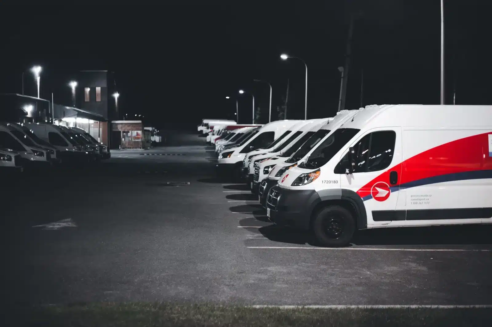 Gestionnaire de flotte inspectant une rangée de fourgons utilitaires garés sur un parking d'entreprise