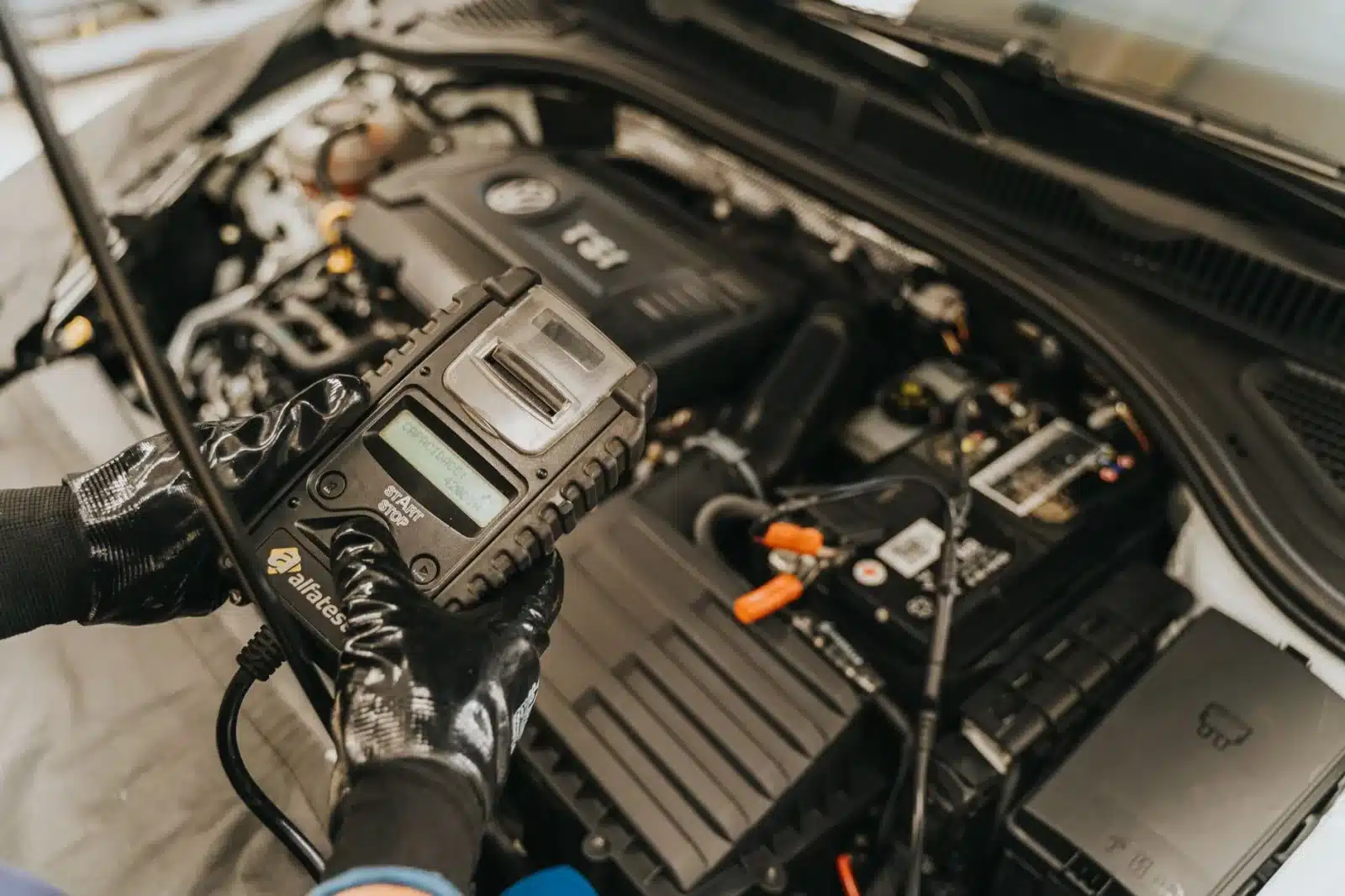 Mécanicien branchant un outil de diagnostic sur le moteur d'une voiture de sport