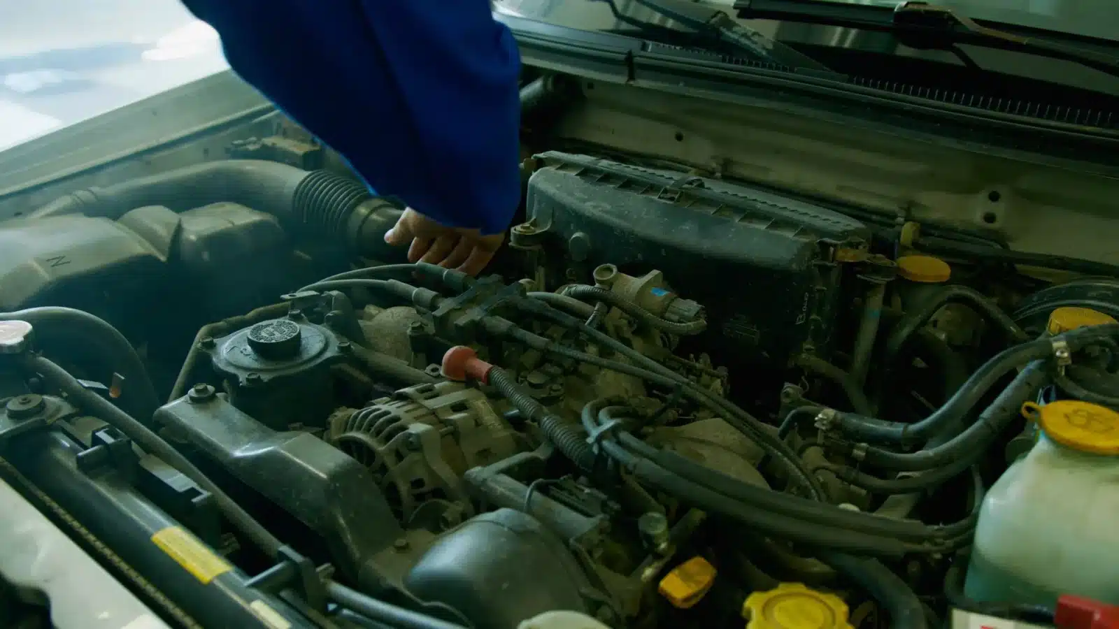 Mécanicien utilisant une valise de diagnostic OBD2 sur le moteur d'une voiture en garage