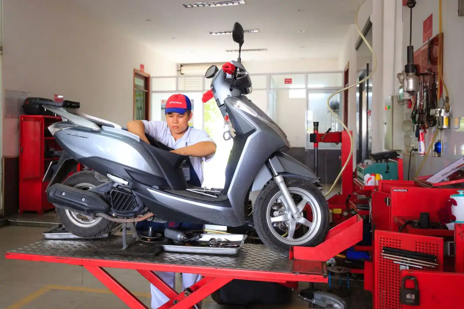 Mécanicien vérifiant la tension de chaîne d'une moto dans un garage