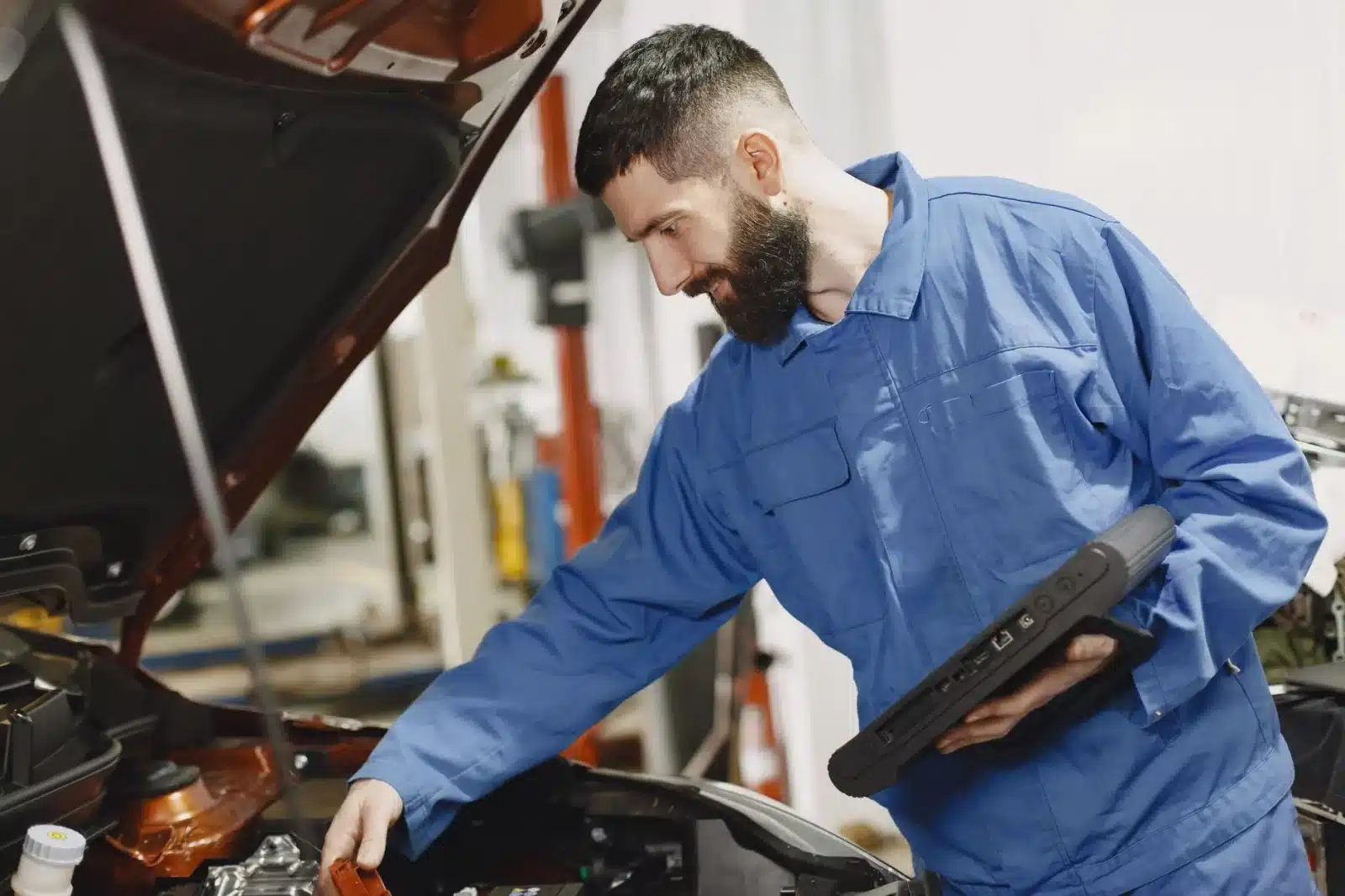 Mécanicien vérifiant le moteur d'une voiture avec un outil de diagnostic