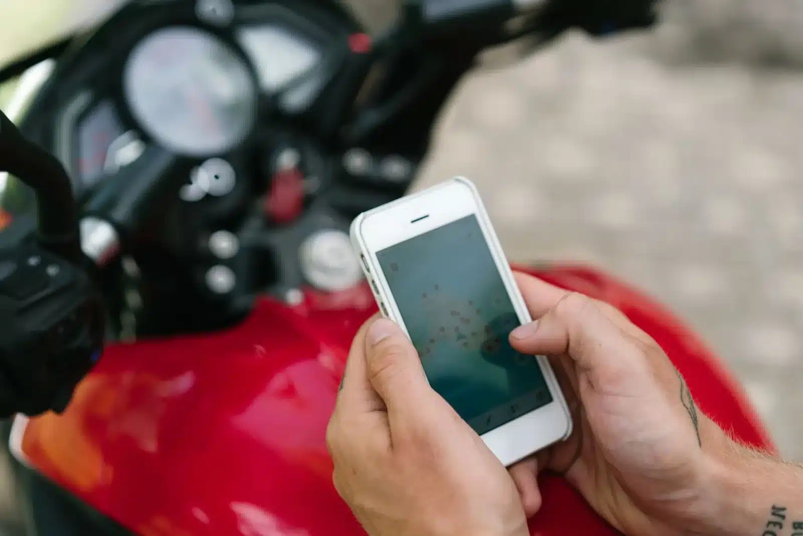 Motard en pause sur une route de montagne, vérifiant son itinéraire sur smartphone