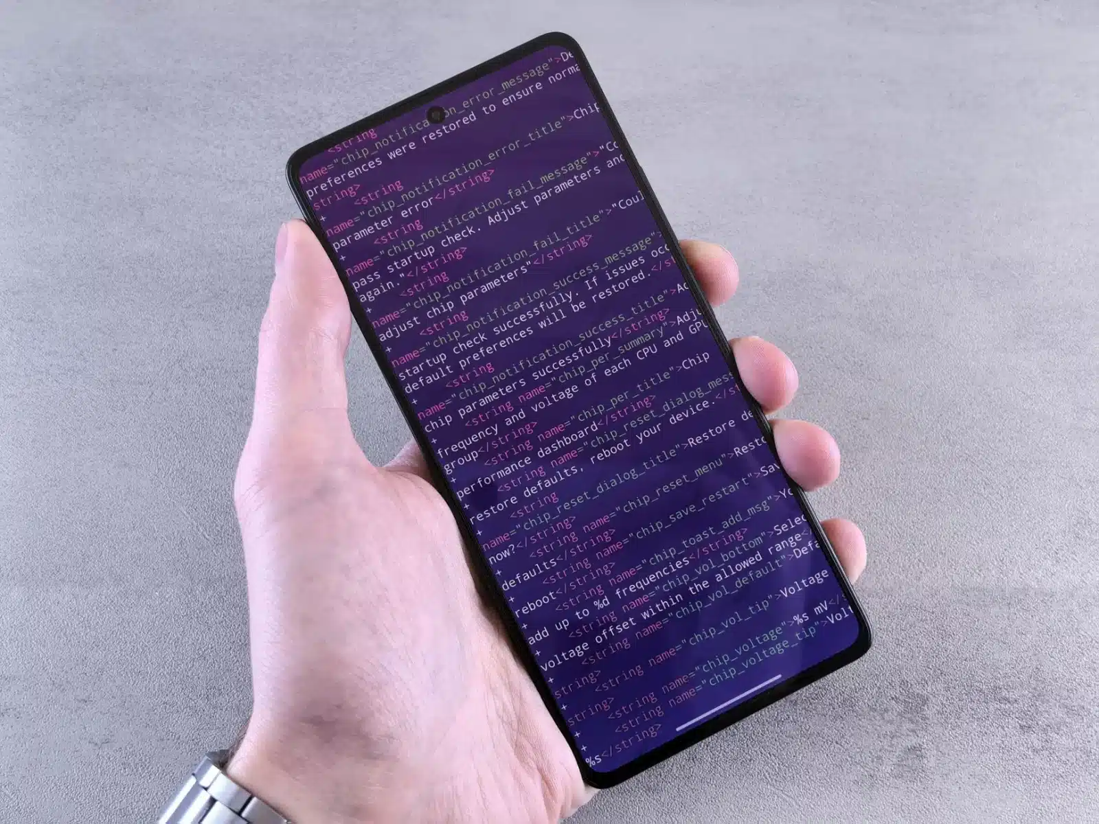 Smartphone affichant un code défaut P0420 via une appli OBD, moteur de voiture en arrière-plan