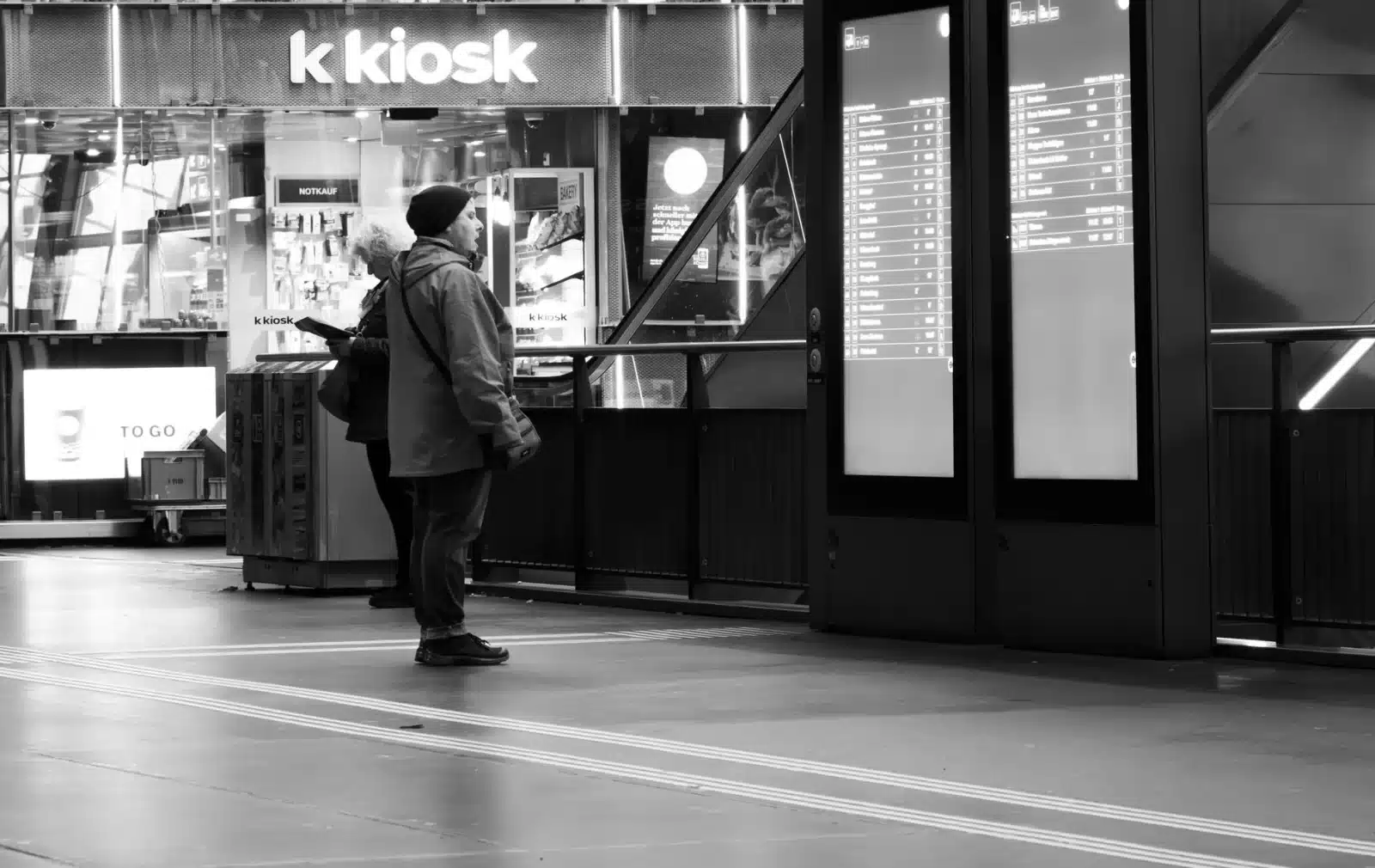 Un usager consulte les horaires de train sur un écran en gare