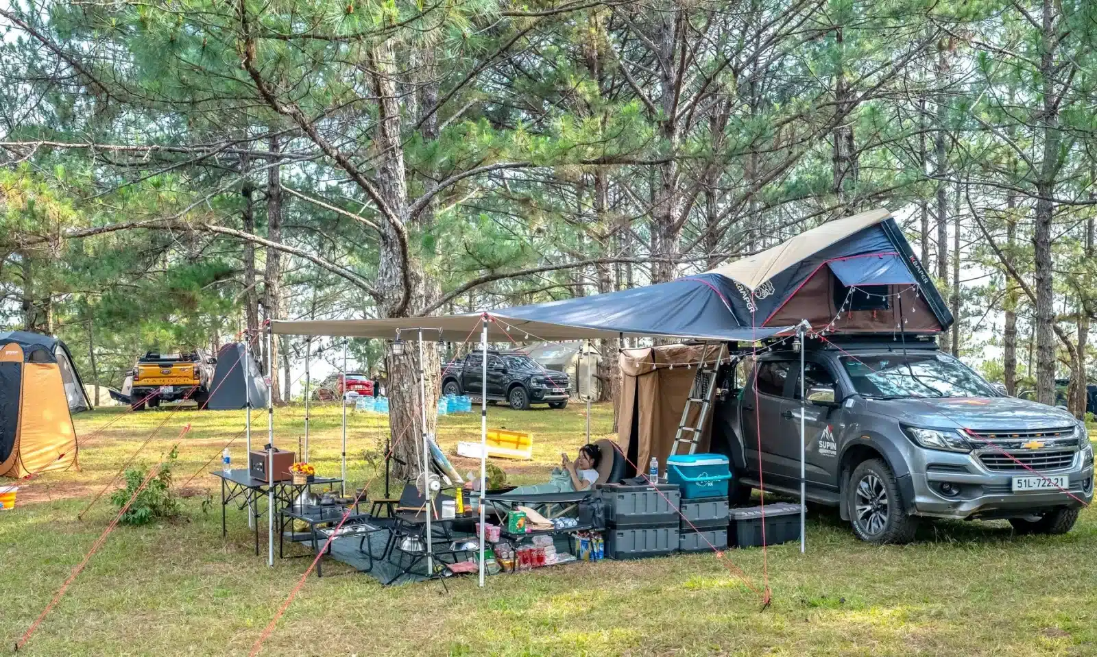 Camping-car avec auvent déployé dans un parking, à côté d'un panneau interdisant le camping