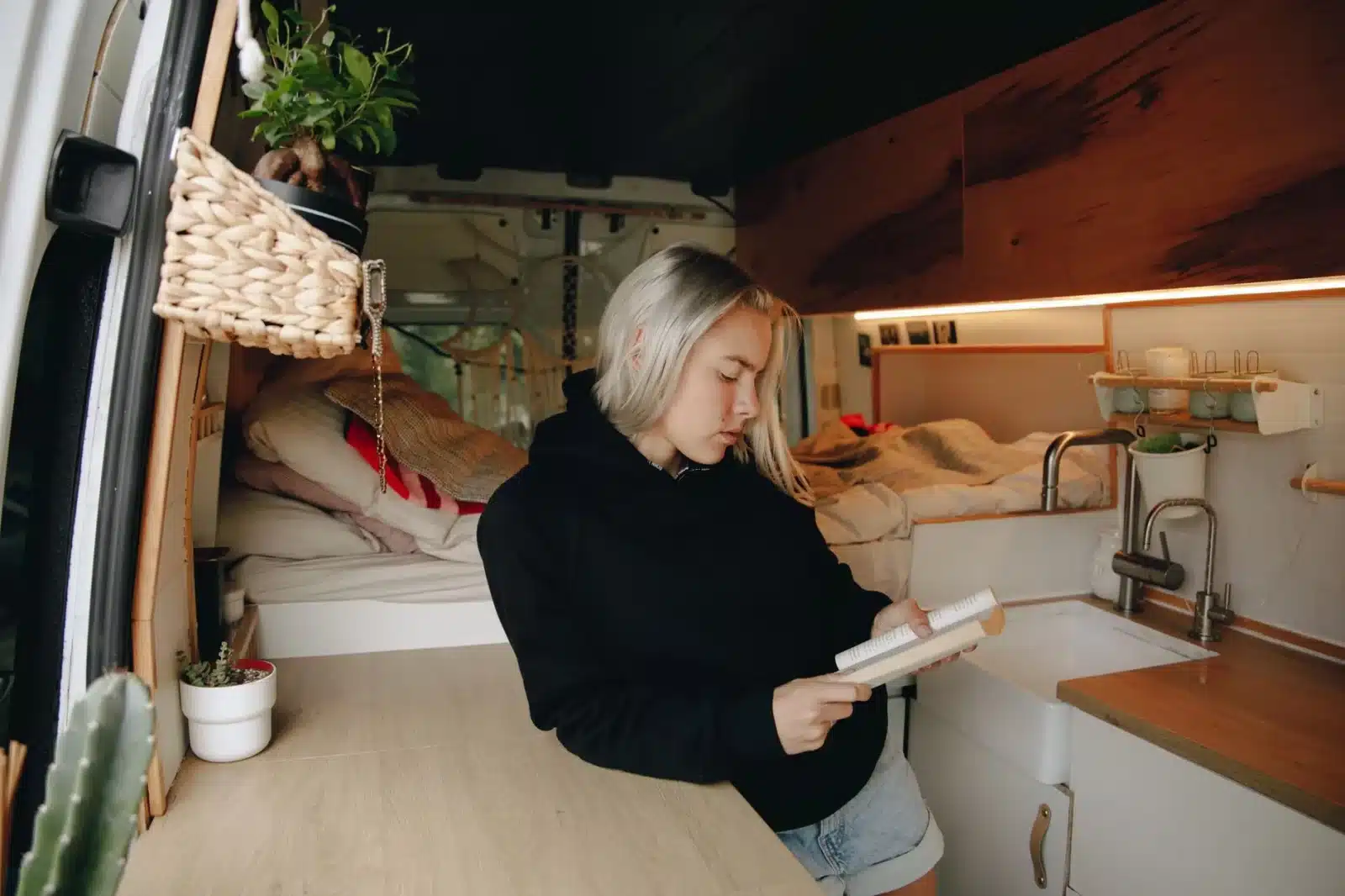 Intérieur d'un fourgon aménagé avec cuisine fixe et lit en bois clair