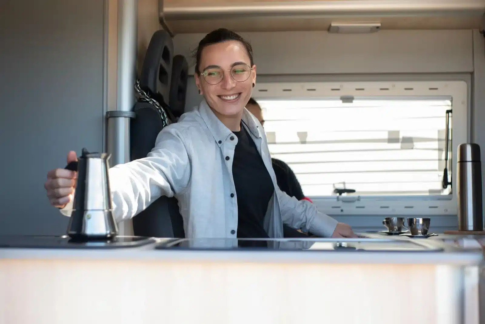 Intérieur d’un fourgon aménagé avec une cuisine fixe en bois et un lit convertible en banquette