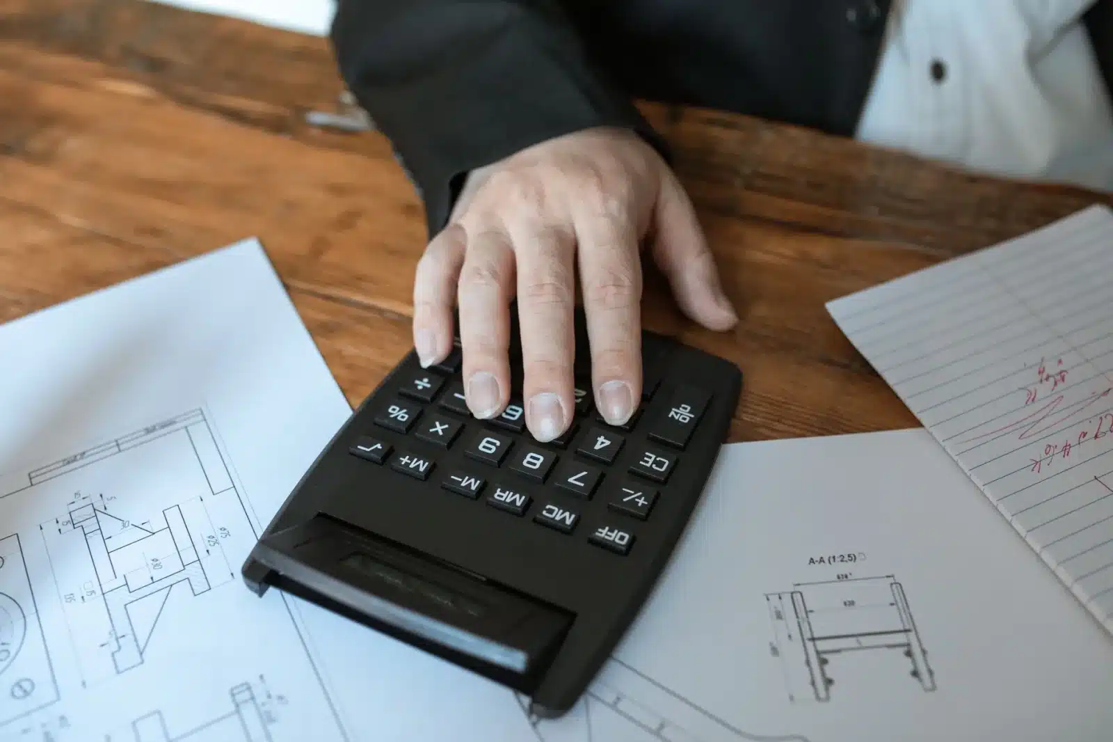 Main tenant un stylo au-dessus d'un tableur avec calculs de loyers déductibles et exonération TVS