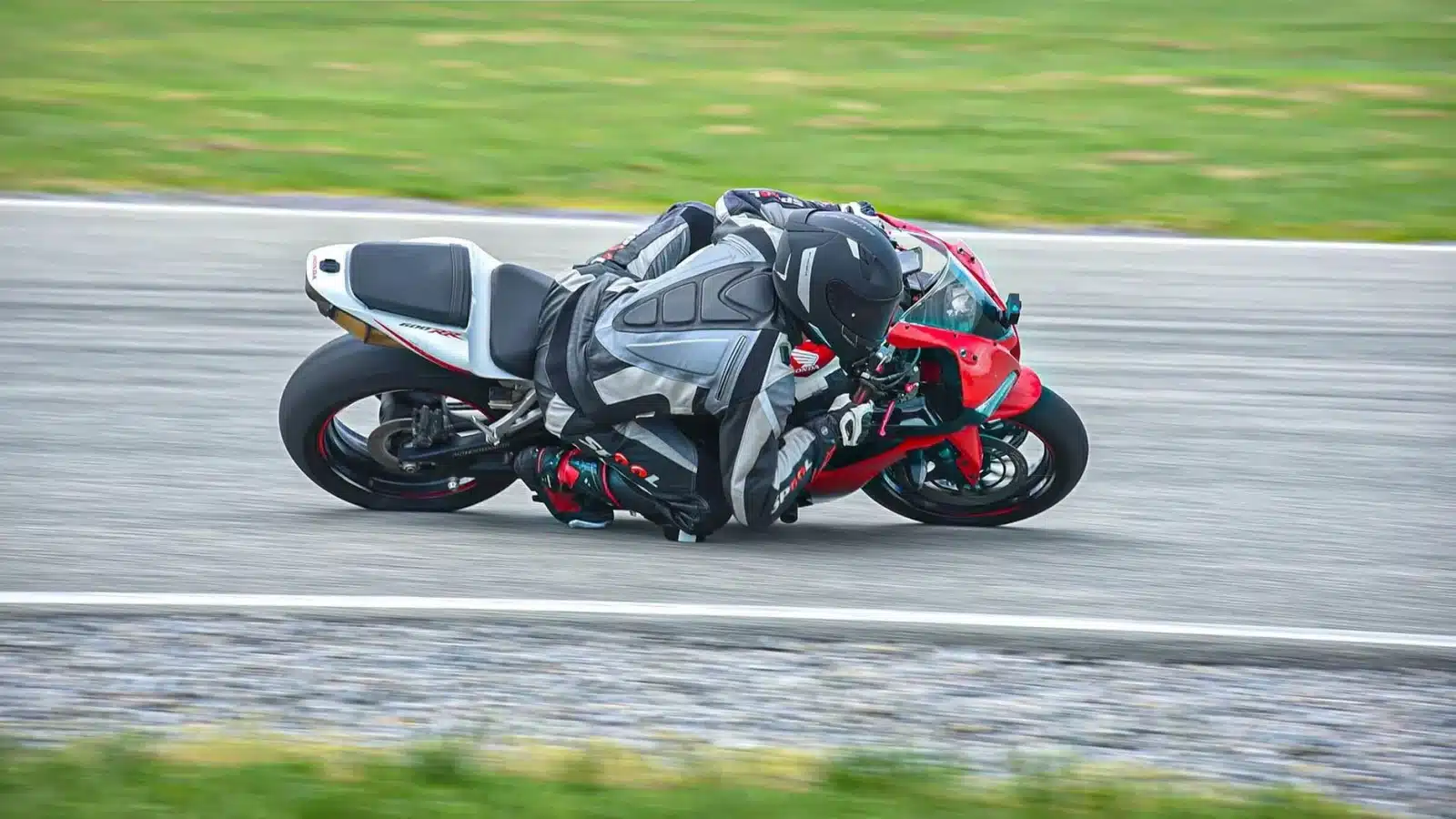 Motard équipé d'un casque intégral et d'une combinaison en cuir sur circuit