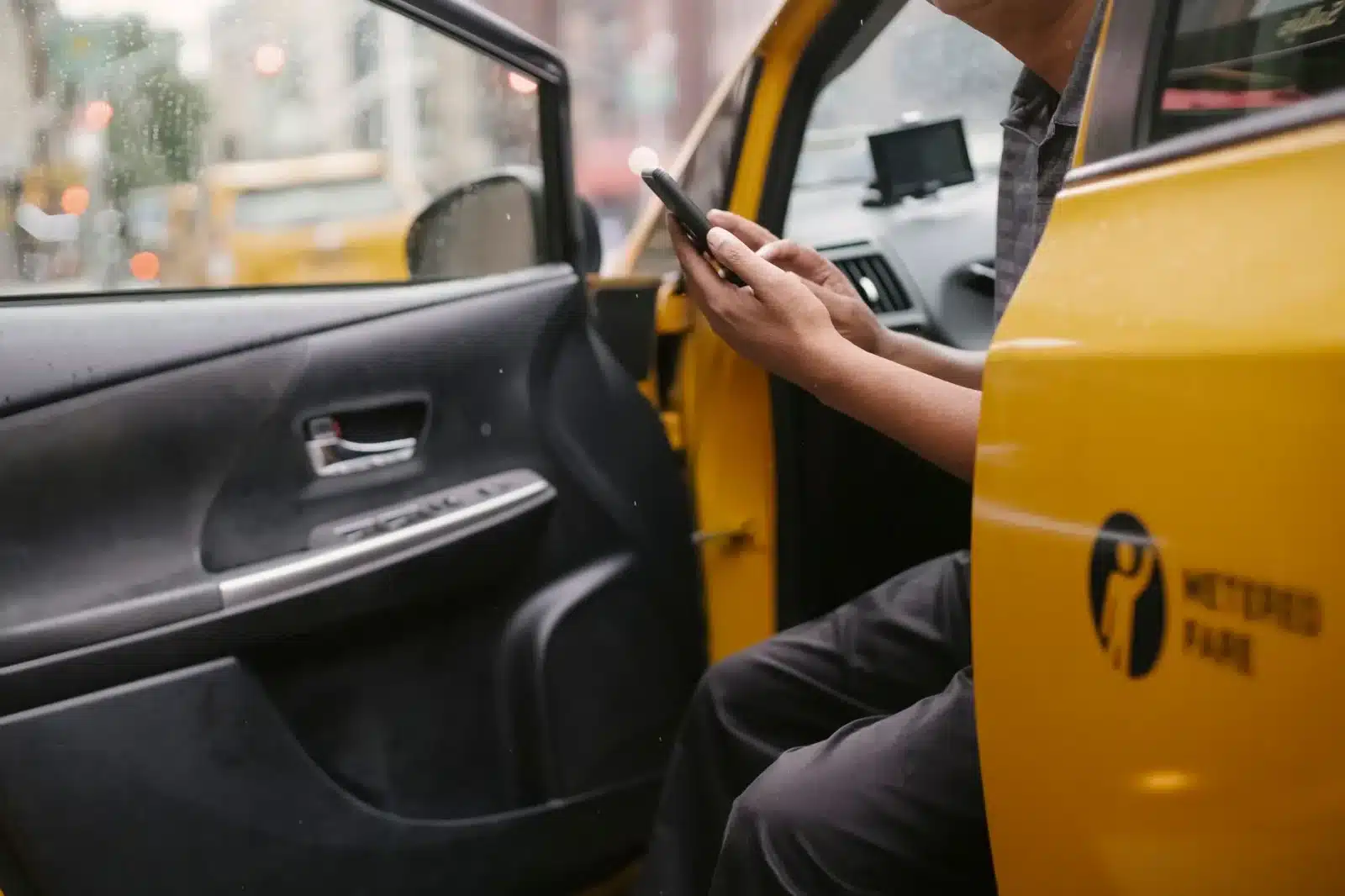 Utilisateur consultant une appli de covoiturage sur son smartphone près d'une voiture