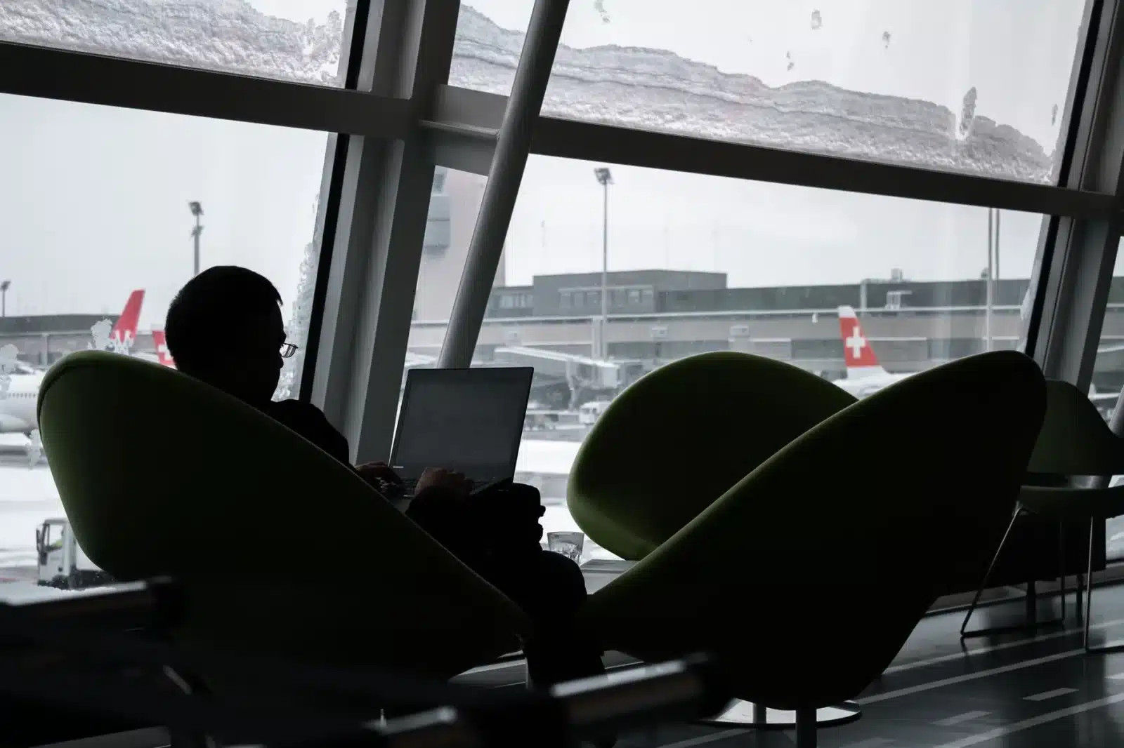 Voyageur comparant les prix de location de voiture sur un ordinateur portable à un comptoir d'aéroport